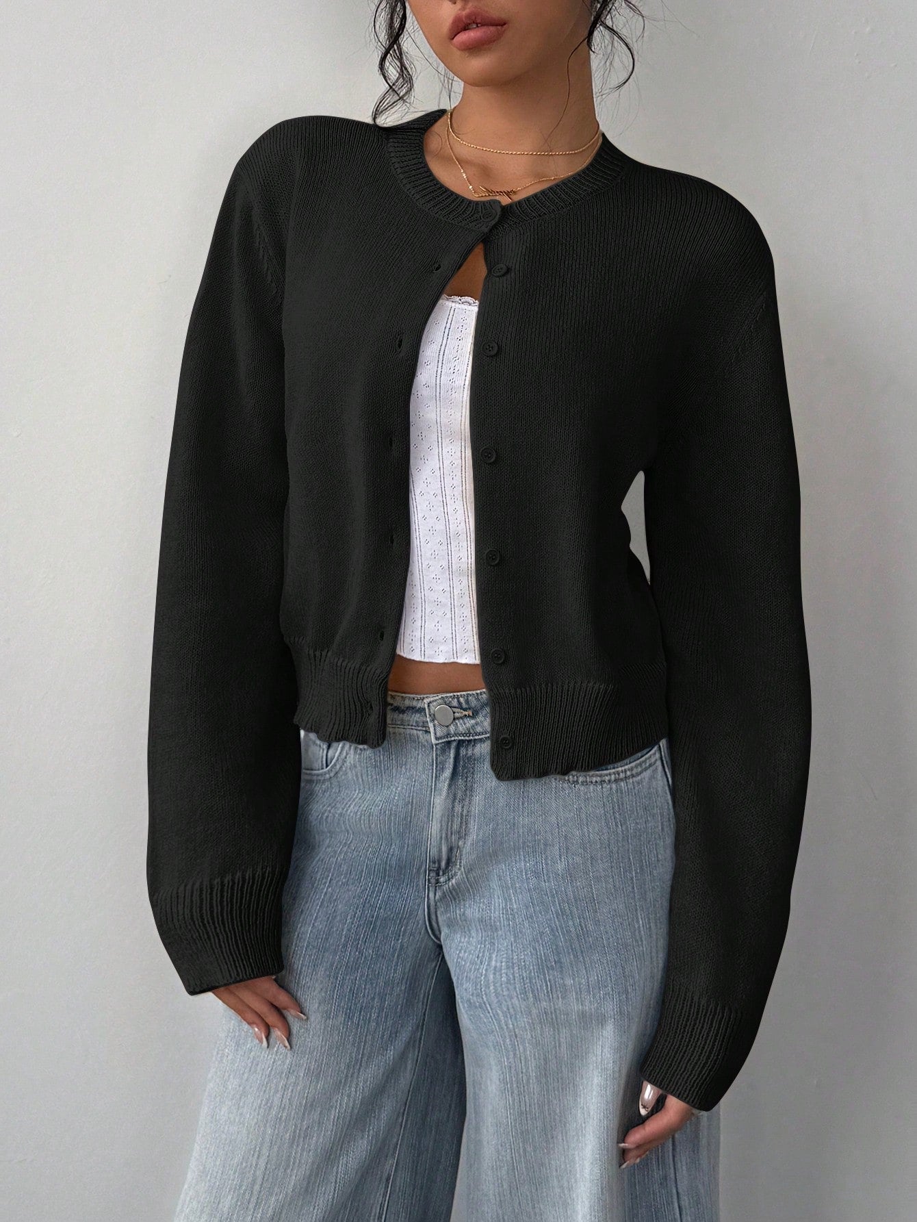 Model wearing a buttoned-up short slim fit long sleeve cardigan in [Color] with high-waisted jeans.