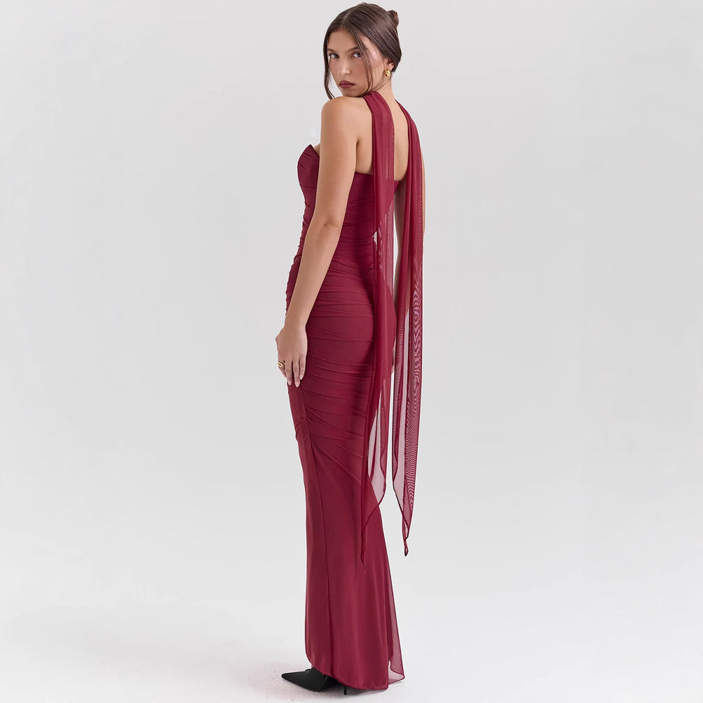 Woman wearing a burgundy evening gown with sheer sides on a white background