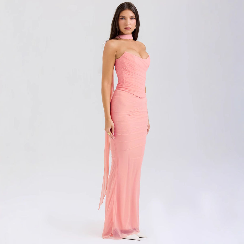 Woman wearing a pink strapless gown with a slit on a white background